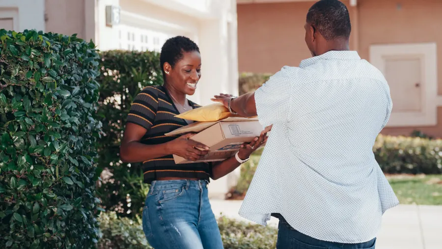 Colis remis en main propre à une femme souriante, en plein soleil